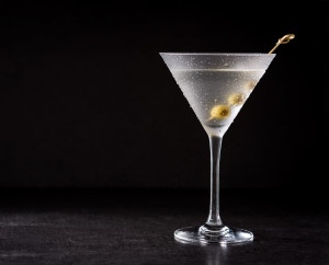Classic Dry Martini with olives on black background. Copyspace